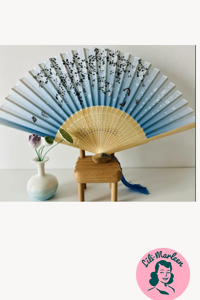 Blå vifte med sommerfugle og blade – stille elegance og sval sommerluft